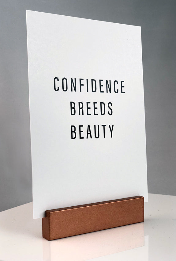 Sign stand with print inserted. Confidence Breeds Beauty